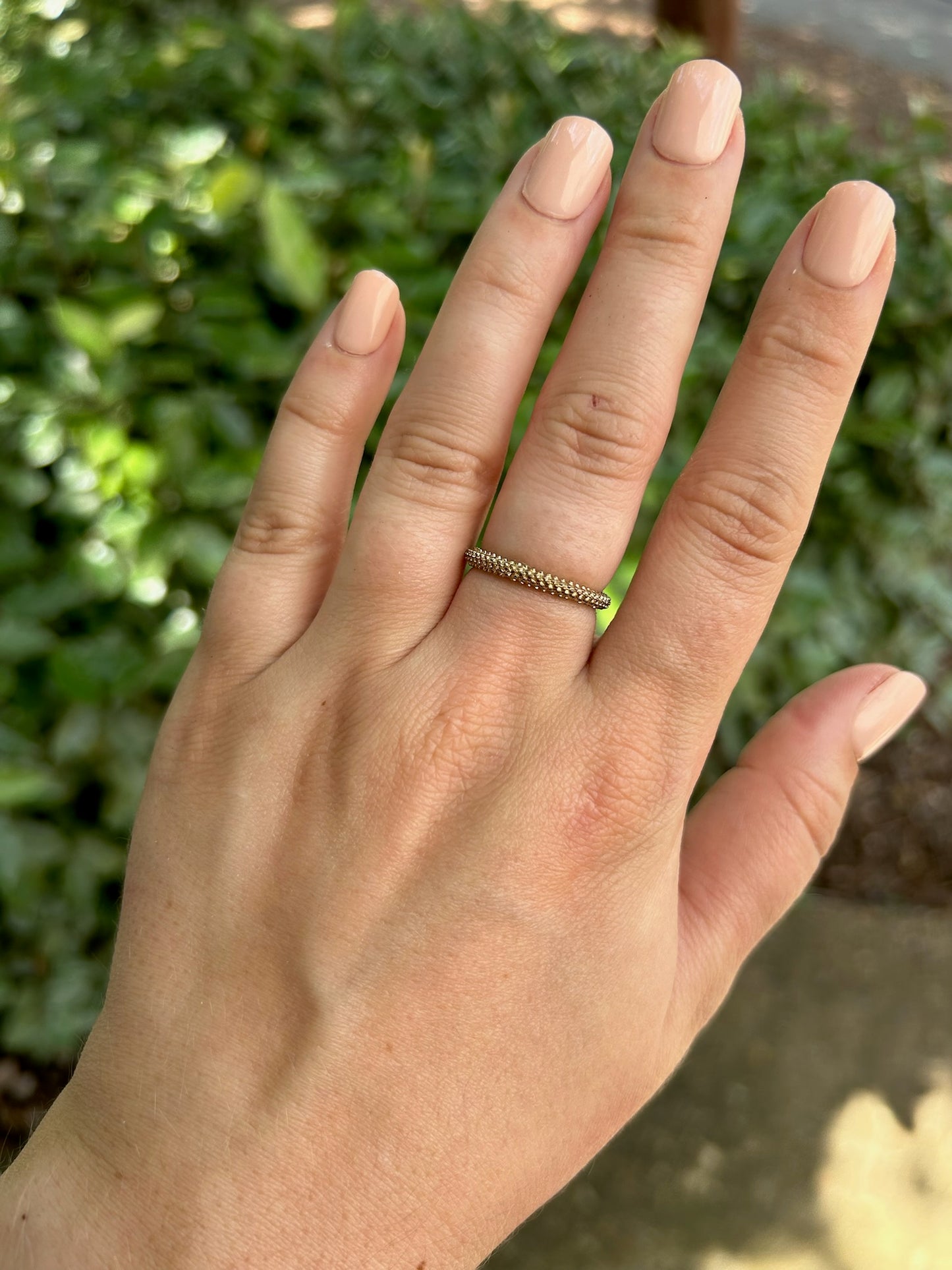 A close-up image of a Rough-Around-the-Edges Ring from Canyon Jewelry, with small clear gemstones, placed on a moss-covered rock surface, showcasing its vintage jewelry charm against a soft-focus background.