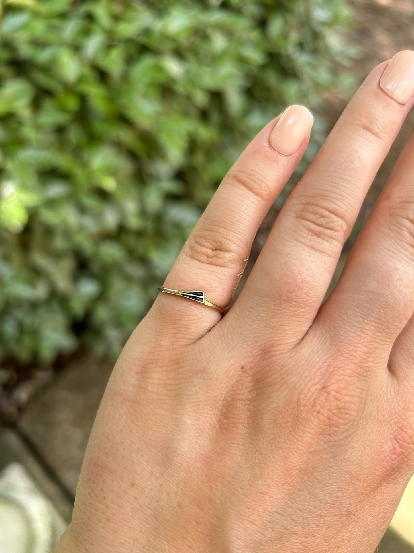 A close-up of a Canyon Jewelry Flagship Ring with a heart-shaped black gem, crafted from sterling silver, resting on a textured, mossy rock surface with a blurred background.