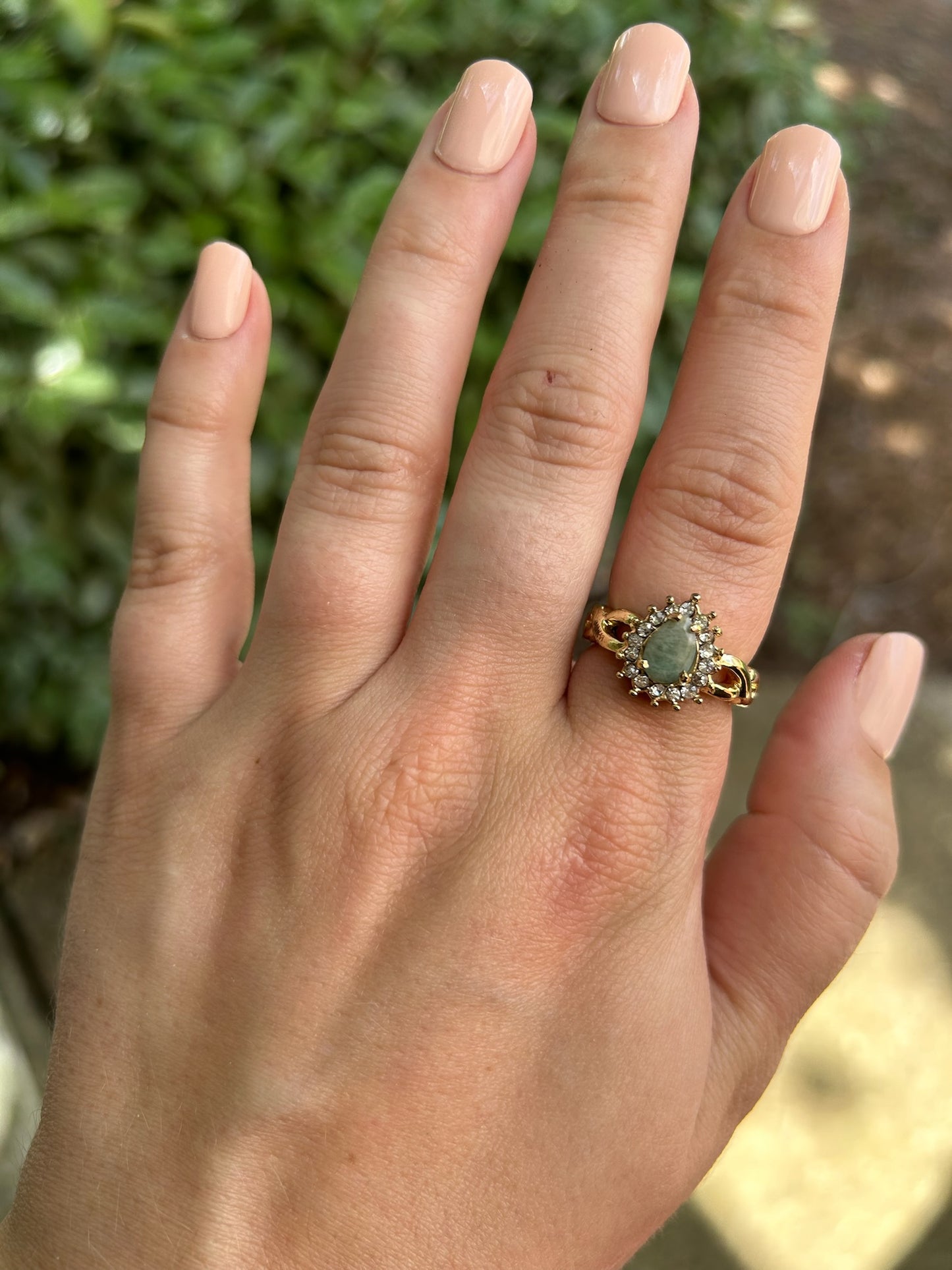 A close-up of an elegant Canyon Jewelry Pastel Pasture Ring with an oval aquamarine stone surrounded by small diamonds, resting on a moss-covered stone surface.
