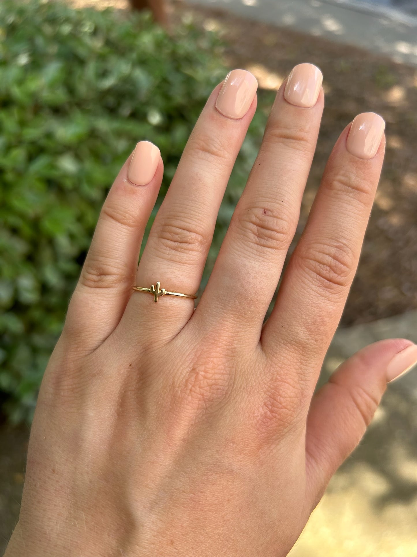 A close-up image of a delicate Canyon Jewelry sterling silver Cactus Ring with a cactus-shaped motif on top, resting on a mossy surface with a blurred background.