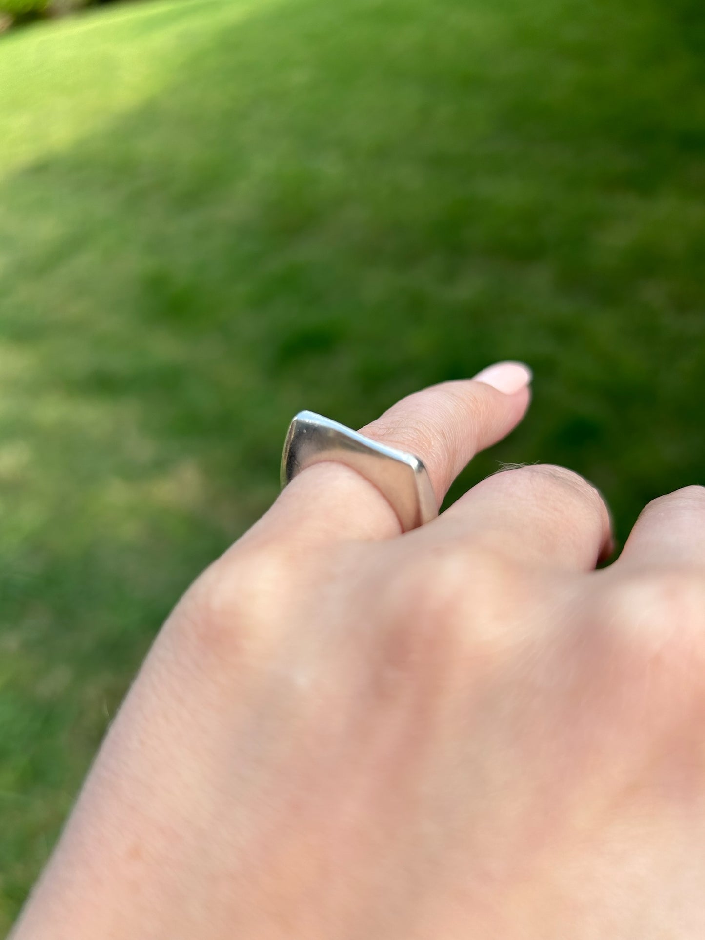 Close-up of a Manifest ring by Canyon Jewelry embedded in a moss-covered stone surface, showcasing fine details and boho textures with a blurred background.
