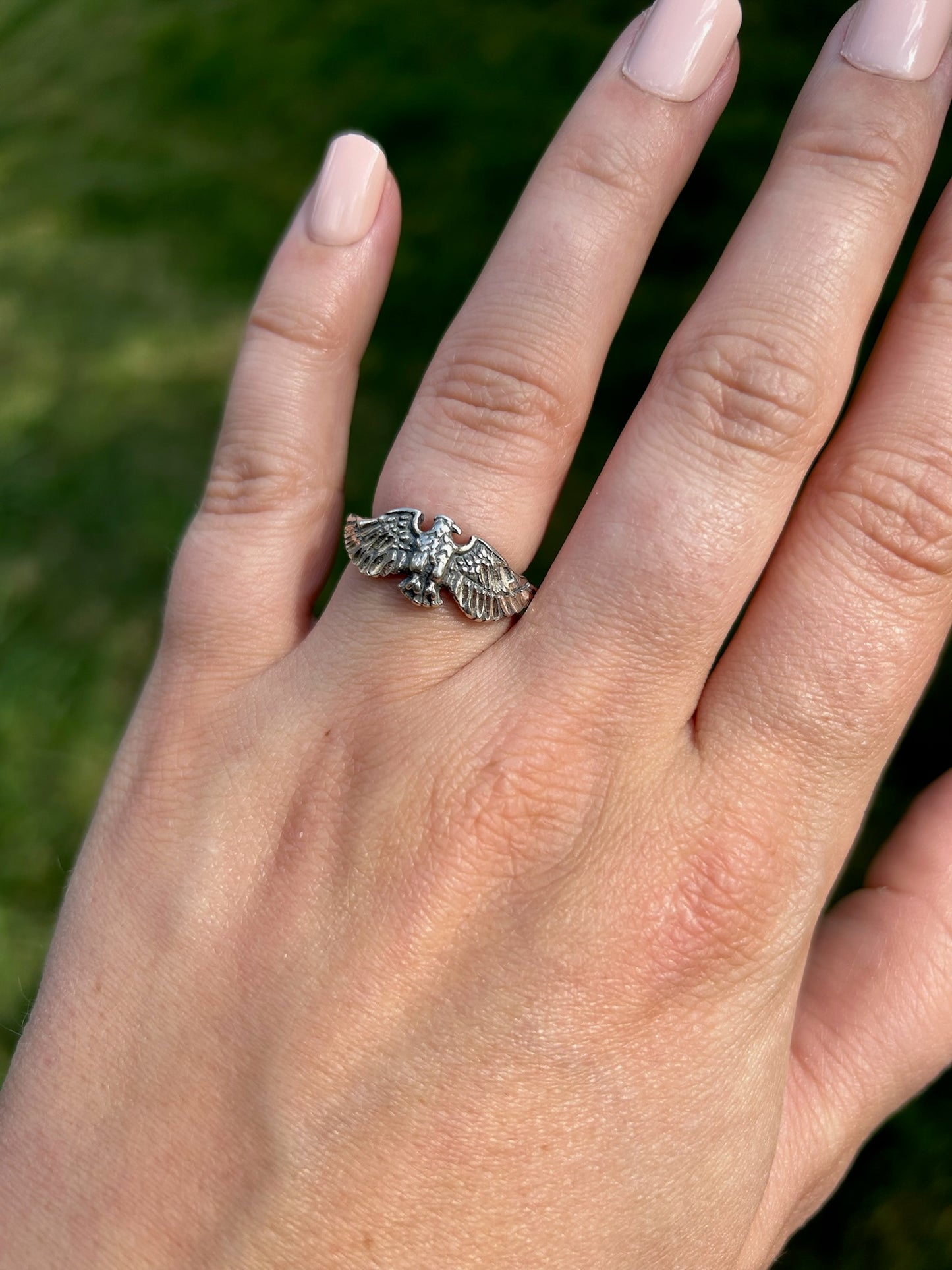 Close-up of a Canyon Jewelry sterling silver Eagle Ring resting on a mossy surface, focusing sharply on the detailed wings and body of the eagle, with a softly blurred background.