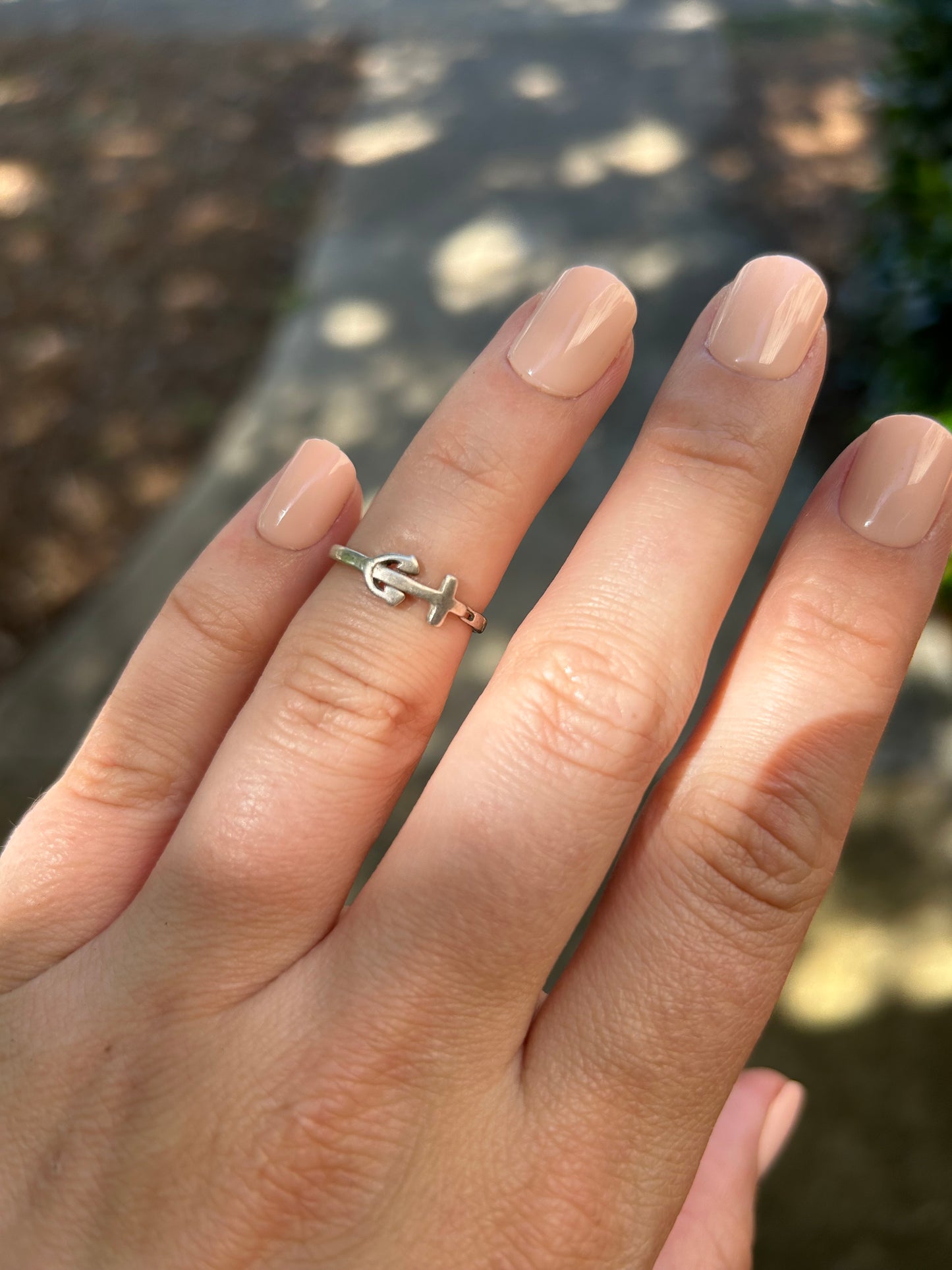 Close-up of a Canyon Jewelry anchor ring with a peace symbol design resting on a moss-covered surface, with a soft focus background.