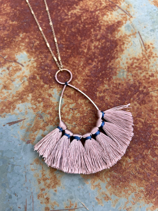 A Pale Light Fringe Necklace with navy blue thread accents, displayed on a rusted metal surface. The necklace features a sterling silver chain looped through a metal ring.