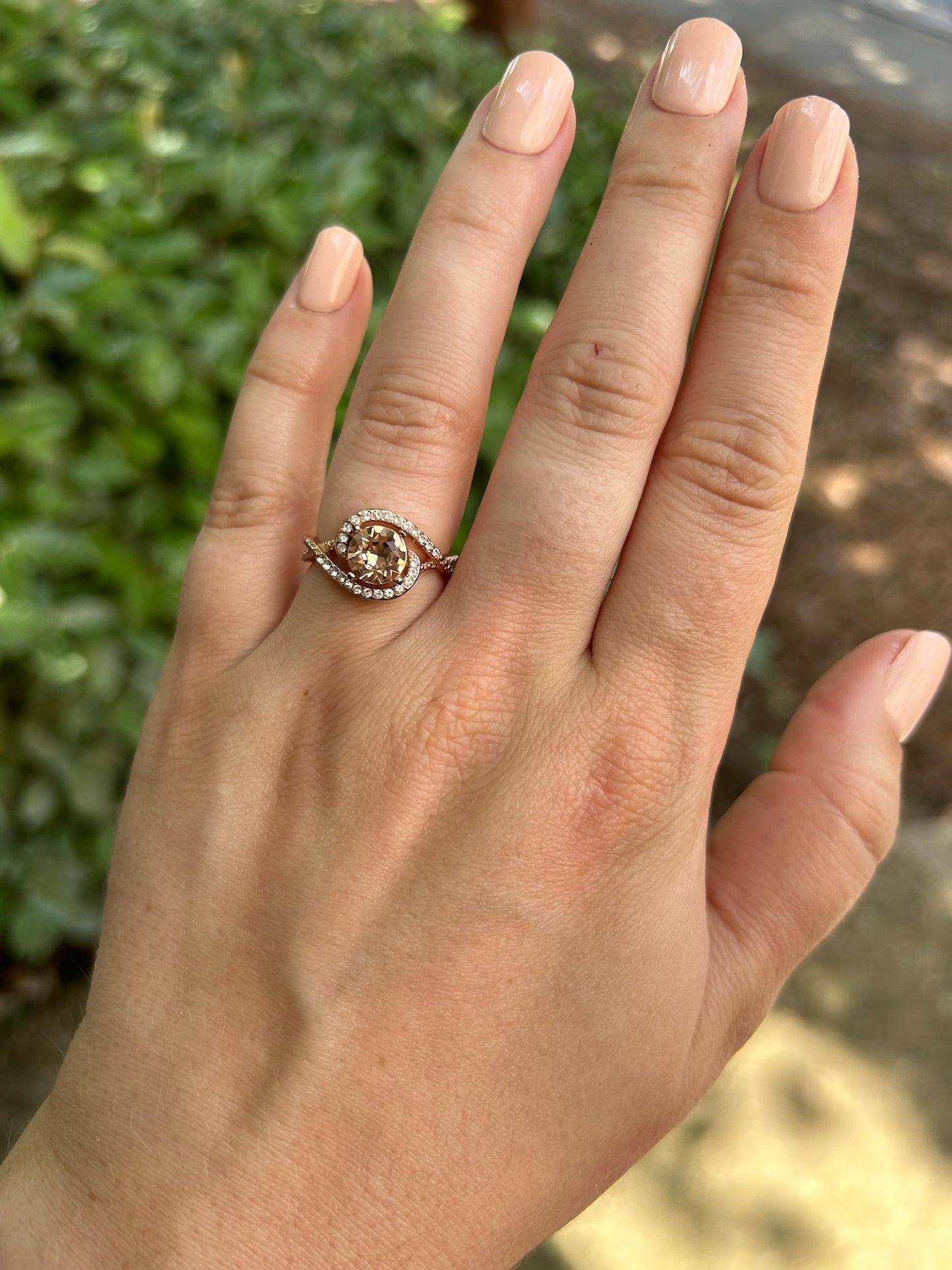 Close-up of a sparkling round-cut Hold Me Closely Ring from Canyon Jewelry, with a sterling silver band, encircled by smaller diamonds. It rests on a moss-covered surface, creating a natural contrast.