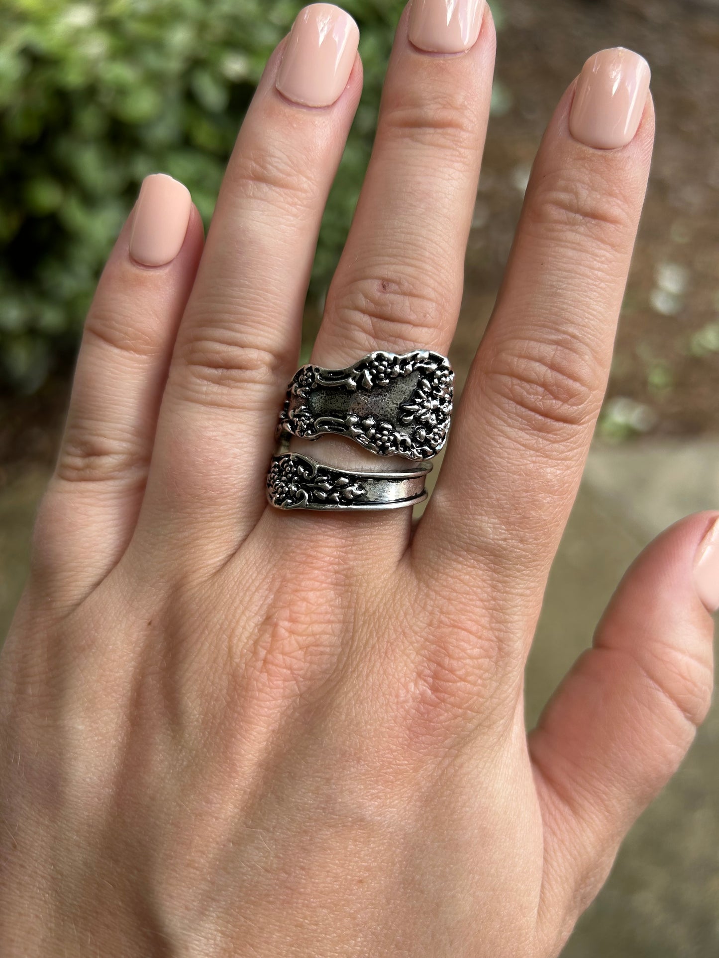 Close-up of an intricately detailed Canyon Jewelry Antoinette Spoon Ring with floral patterns, resting on a vibrant green mossy surface.