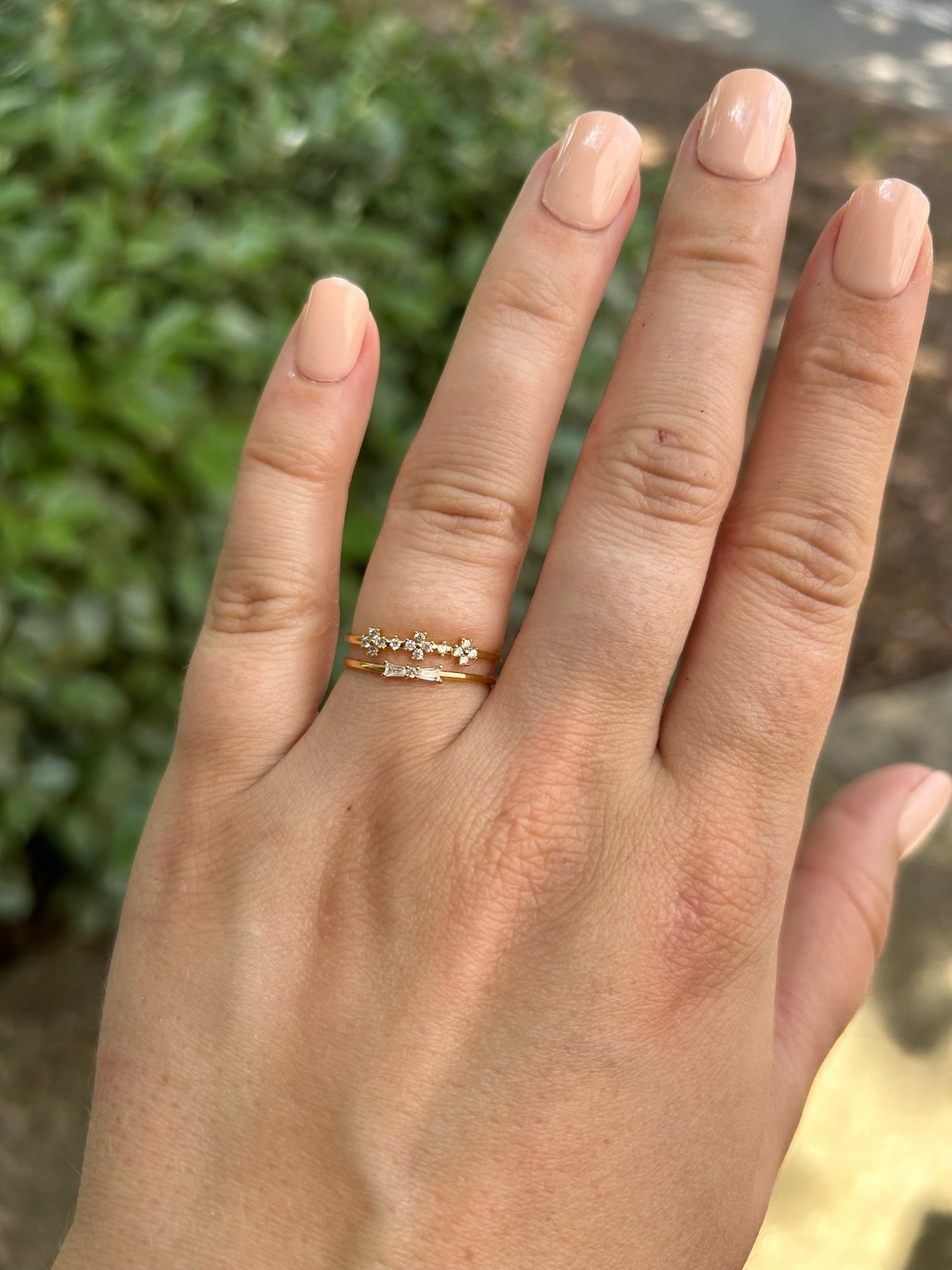 Close-up of two elegant Canyon Jewelry Mata Hari Rings with diamonds, placed on a textured surface that looks like moss, with a beautifully blurred background emphasizing the jewelry's sparkle.